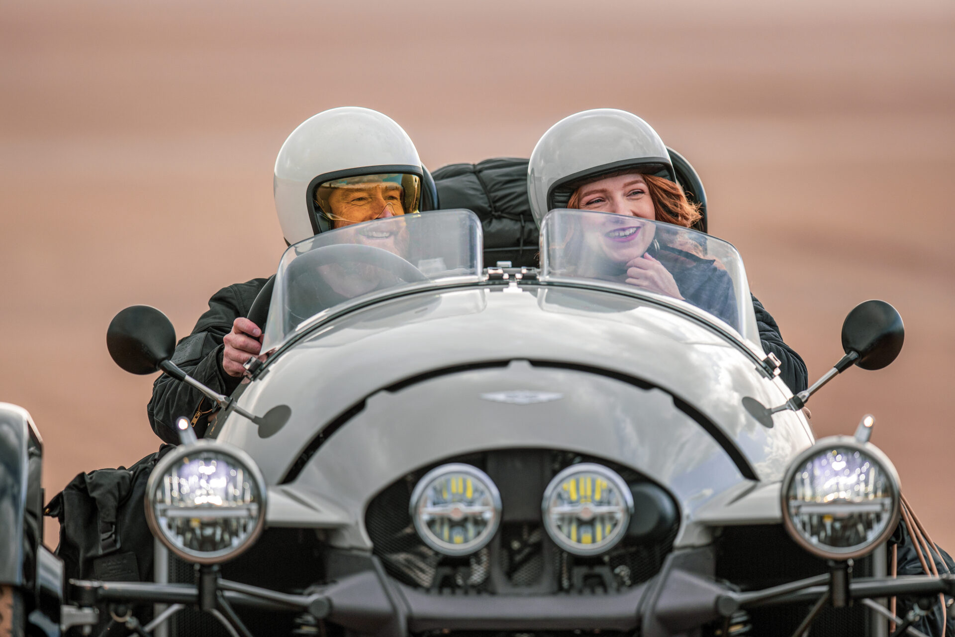 Couple driving Super 3 on a beach.